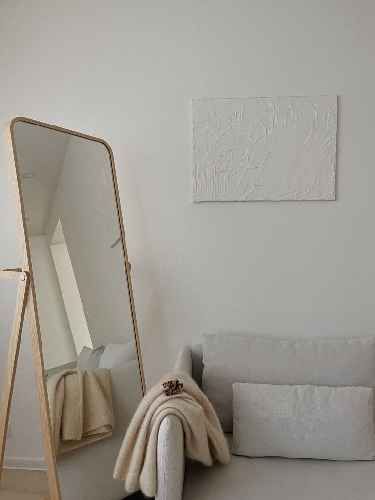 A cozy minimalist living room with a mirror reflecting light, promoting a warm and soothing atmosphere.